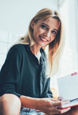 Samimi gülüşü olan güzel bir hippi kız. Üniversite ödevlerini yaparken kameraya bakıyor. Ders kitabı, elinde not defteriyle kafede mutlu bir ruh halinin keyfini çıkaran neşeli bir kız.