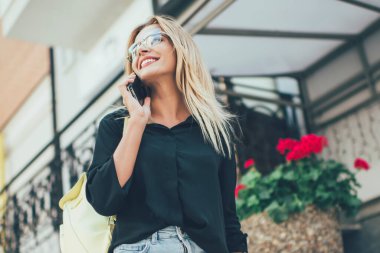 Heyecanlı kadın gezginlerin günlük kıyafetleriyle en iyi arkadaşına yaz tatilleri hakkındaki izlenimlerini paylaşması için seslenmesinin altında, pozitif hipster kız uluslararası arama için gezici bağlantısını kullanıyor.