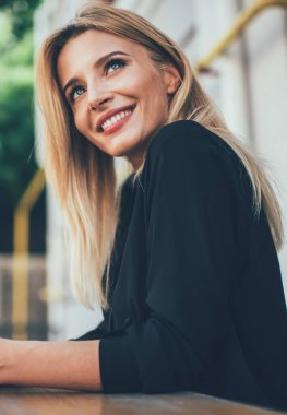 Teknoloji ve nesil kavramı, açık havada dinlenirken yüzünü çeviren samimi gülümsemesi olan çekici bir kadın. Çevrimiçi iletişim için cep telefonu tutan pozitif sarışın hippi kız.