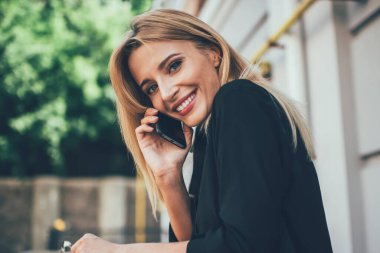 Sokak kafeteryasında otururken kameraya bakan mutlu bir kadının portresi uluslararası arama yapmak için halk interneti kullanıyor, neşeli bir kadın kablosuz ve uygulamayla arkadaşlarıyla iletişim kuruyor.