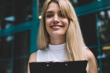 Çekici genç kadın gülümsüyor ve masaya oturan iken masanın içinde açık kafede dizüstü içine panoya veri aktarımı oturuyor