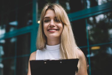 Çekici genç kadın gülümsüyor ve masaya oturan iken masanın içinde açık kafede dizüstü içine panoya veri aktarımı oturuyor