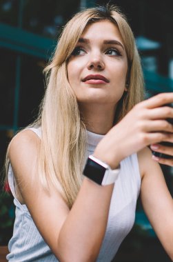 Akıllı telefon kullanarak sarı saçlı çekici genç kadın ve rahat açık kafede masada serbest iş yaparken hayal uzağa bakıyor