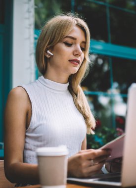 Masada otururken ve rahat açık kafede serbest iş yaparken Not defteri dizüstü okuma notları ile çekici genç kadın