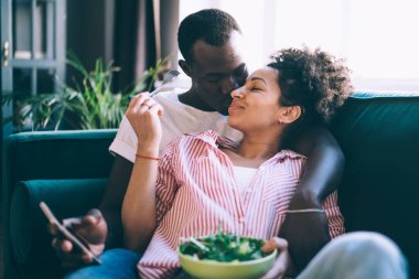 Barışçıl, etnik çeşitlilikte insanlar birbirleriyle öpüşüp salata yerken ve hafta sonları evde akıllı telefon kullanırken.