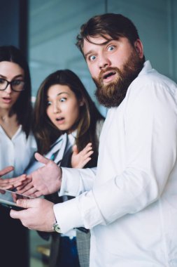 Çeşitli küçük ofis çalışanlarından oluşan bir grup modern ofiste durup kameraya bakarken tablette sunulan işle ilgili bilgiler hakkında konuşuyorlardı.