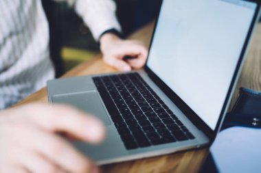 Çizgili gömlekli tanımlanamayan bir ofis çalışanı açık dizüstü bilgisayarın önünde oturuyor ve arka planda boş bir ekran var.