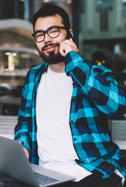 Sakallı kazak hippi adam dışarıda kafede dinleniyor ve akıllı telefonla konuşuyor. Arkadaşı dizüstü bilgisayarında oturuyor. Yakışıklı genç serbest çalışan adam uzaktan kumanda sırasında cep telefonundan arıyor.