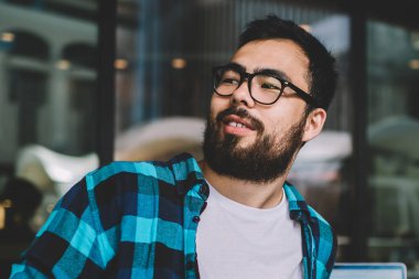 Asyalı, sakallı hippi, şehir merkezlerinde kahve molası veriyor. İnternette sohbet etmek için cep telefonu kullanıyor. Elinde akıllı telefonu olan yakışıklı bir blog yazarı var.