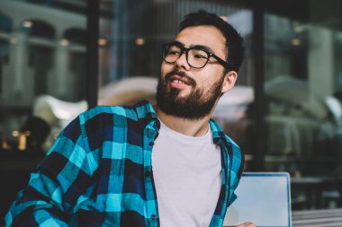 Asyalı, sakallı hippi, şehir merkezlerinde kahve molası veriyor. İnternette sohbet etmek için cep telefonu kullanıyor. Elinde akıllı telefonu olan yakışıklı bir blog yazarı var.