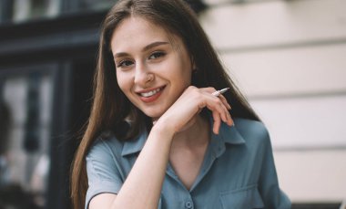 İlginç olumlu makaleler yaratmak için dizüstü bilgisayar ve ders kitabı kullanan çekici gülümseyen kadın metin yazarının portresi, Kafkasyalı serbest yazarların sokak kafeteryasında zaman geçirmesi