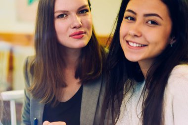 İş ortaklarının birlikte çalışma alanında buluşurken kameraya baktıkları pozitiflik portresi, atölyede birlikte çalışmaktan zevk alan mutlu beyaz kadınlar.