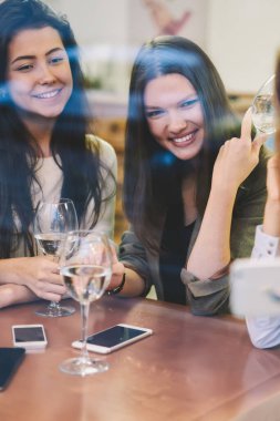 Kafeteryada boş zamanlarında selfie için poz veren pozitif kadın blogcular, arkadaşlarıyla evde otururken modern cep telefonunda fotoğraf çeken mutlu bir kadın.