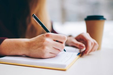 Seçici odaklanma kapalı eğitim için ders kitabına bilgi yazmak kaliteli siyah kalem kullanarak, Kafeterya masasında oturan kadın görüntüsü kafeterya not defteri ile