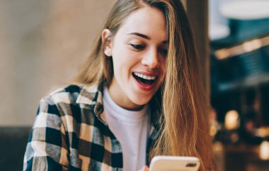 Mutlu hipster kızı, üniversite oturumuyla ilgili bilgilerin cep telefonuyla 4G kablosuz bağlantısıyla aldığı e-postadan şok olmuş hissediyor.