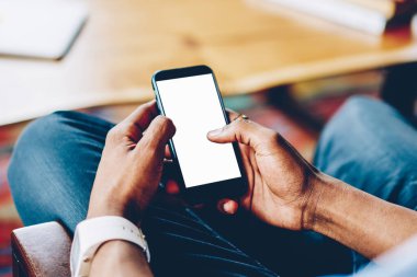 Yukarıdaki cep telefonundan, Afrika kökenli Amerikalı birinin elinde. Masada oturmuş, toplantı sırasında bilgi sörfü yapıyor.