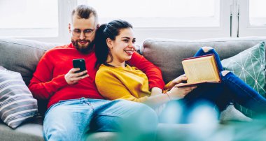 Genç hippi çift rahat bir kanepede hobi ve ilişkilerden tatmin olurken, kız arkadaşı kanepede oturmuş kitap okurken pozitif adamın cep telefonuyla sohbet etmesi.