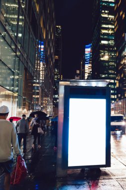 Reklam veya promosyon içeriği için boş kopya boşluk ekranı ile yağmurlu gece otobüs terminali Billboard, bilgi için lightbox kadar boş sahte, uzun pozlama ile kentsel şehir sokakta boş ekran