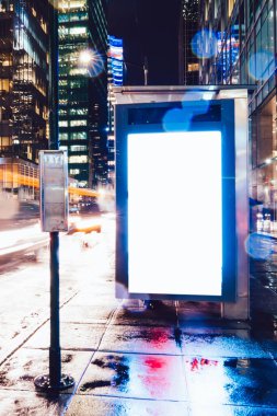 Reklam veya promosyon içeriği için boş kopya boşluk ekranı ile yağmurlu gece otobüs terminali Billboard, bilgi için lightbox kadar boş sahte, uzun pozlama ile kentsel şehir sokakta boş ekran