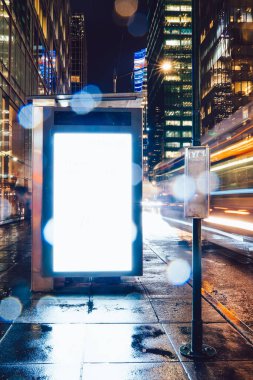 Reklam veya promosyon içeriği için boş kopya boşluk ekranı ile yağmurlu gece otobüs terminali Billboard, bilgi için lightbox kadar boş sahte, uzun pozlama ile kentsel şehir sokakta boş ekran