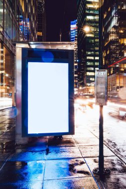 Reklam veya promosyon içeriği için boş kopya boşluk ekranı ile yağmurlu gece otobüs terminali Billboard, bilgi için lightbox kadar boş sahte, uzun pozlama ile kentsel şehir sokakta boş ekran