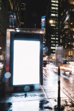 Reklam veya promosyon içeriği için boş kopya boşluk ekranı ile yağmurlu gece otobüs terminali Billboard, bilgi için lightbox kadar boş sahte, uzun pozlama ile kentsel şehir sokakta boş ekran