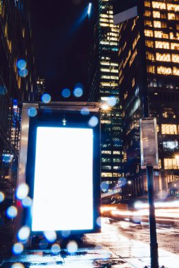 Reklam veya promosyon içeriği için boş kopya boşluk ekranı ile yağmurlu gece otobüs terminali Billboard, bilgi için lightbox kadar boş sahte, uzun pozlama ile kentsel şehir sokakta boş ekran