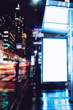 Reklam veya promosyon içeriği için boş kopya boşluk ekranı ile yağmurlu gece otobüs terminali Billboard, bilgi için lightbox kadar boş sahte, uzun pozlama ile kentsel şehir sokakta boş ekran
