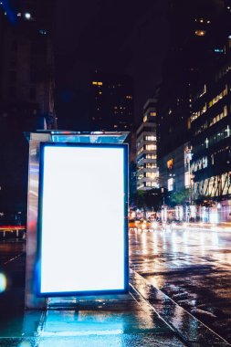 Reklam veya promosyon içeriği için boş kopya boşluk ekranı ile yağmurlu gece otobüs terminali Billboard, bilgi için lightbox kadar boş sahte, uzun pozlama ile kentsel şehir sokakta boş ekran