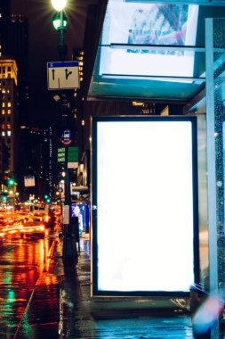 Reklam veya promosyon içeriği için boş kopya boşluk ekranı ile yağmurlu gece otobüs terminali Billboard, bilgi için lightbox kadar boş sahte, uzun pozlama ile kentsel şehir sokakta boş ekran