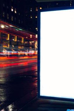 Reklam veya promosyon içeriği için boş kopya boşluk ekranı ile yağmurlu gece otobüs terminali Billboard, bilgi için lightbox kadar boş sahte, uzun pozlama ile kentsel şehir sokakta boş ekran