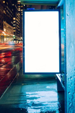Reklam veya promosyon içeriği için boş kopya boşluk ekranı ile yağmurlu gece otobüs terminali Billboard, bilgi için lightbox kadar boş sahte, uzun pozlama ile kentsel şehir sokakta boş ekran