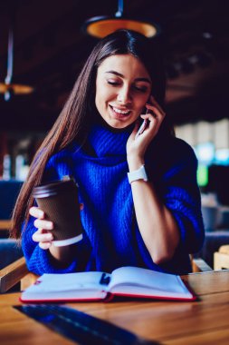 Sabah kahve içme ve konuşma bir arkadaşım cep telefonu üzerinden zevk neşeli kafkas kadın için wifi, modern teknoloji için çağrı kapalı kullanan mutlu gülümseyen hippi kız bağlı.