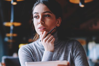 Yeni gadget ile kafede istirahat ederken beyaz esmer kadın düşünceli bir kenara bakıyor, çekici rüya gibi hipster kız planlama yarın listesini kullanarak taşınabilir PC uygulaması iş kapalı mola sırasında