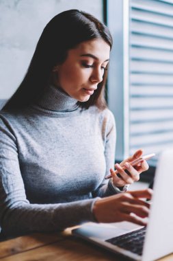 Favori kafeterya otururken ve modern dizüstü bilgisayar üzerinde çalışan meslektaşları ile sohbet için akıllı telefon kullanarak yetenekli güzel kadın grafik tasarımcı, dalgın kadın kontrol e-posta kapalı