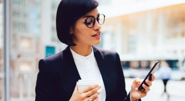 İş yerindeki kahve molası sırasında cep telefonuyla veri servisi hakkında bilgilendirme okuyan genç esmer kadın, internet sitesinde finans haberleri okuyan bin yıllık kadın avukat.