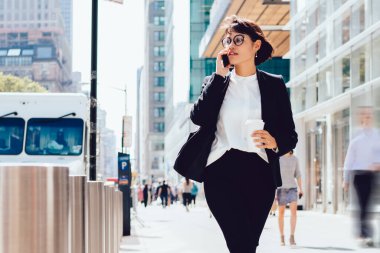 Gözlüklü, şık takım elbiseli, modern New York sokaklarında gezen ve iş ortağıyla uluslararası konuşma yapmak için 4 G 'lik internet bağlantısı kullanan kendine güvenen bir kadın.