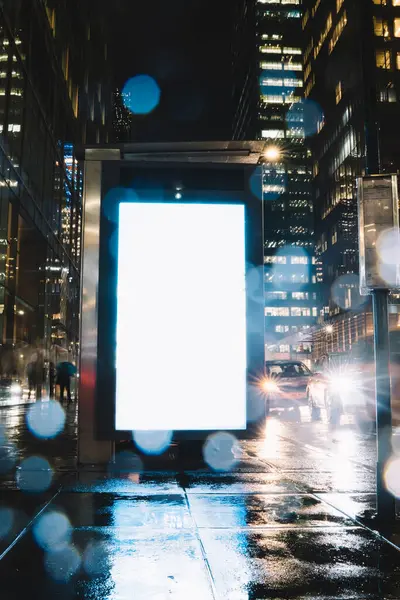 Reklam veya promosyon içeriği için boş kopya boşluk ekranı ile yağmurlu gece otobüs terminali Billboard, bilgi için lightbox kadar boş sahte, uzun pozlama ile kentsel şehir sokakta boş ekran