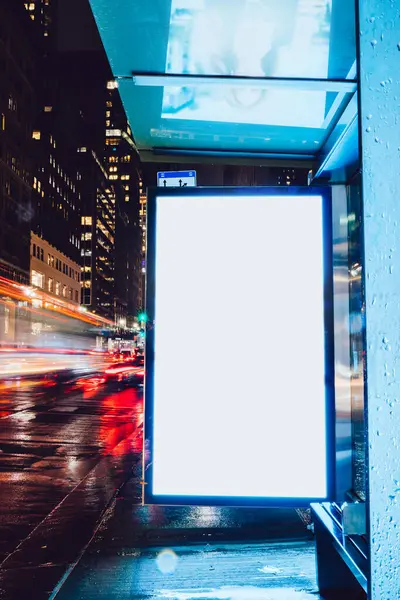 Reklam veya promosyon içeriği için boş kopya boşluk ekranı ile yağmurlu gece otobüs terminali Billboard, bilgi için lightbox kadar boş sahte, uzun pozlama ile kentsel şehir sokakta boş ekran