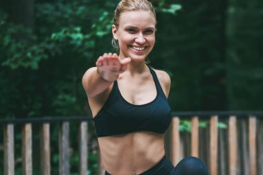 Mutlu kadın portre esneklik geliştirmek ve sağlıklı yaşam yol, pozitif kız doğa ortamında sportif eğitim pratiği sabah enerjik egzersiz sırasında germe egzersizleri yapıyor