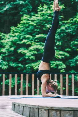 Sarvangasana sabah yoga ayakta ve sağlıklı yaşam tarzı zevk için Sportive kadın atlet harcama zamanı, Genç ince kadın doğa ortamında eğitim için mat omuz standı yapıyor