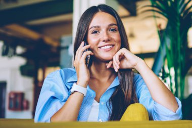 Gülümseyen hipster kız Casual giyinmiş akıllı telefon konuşma işten mutlu haber aldı, pozitif beyaz kadın kablosuz bağlantı kapalı kullanarak uygulama üzerinden hücresel arama yapma