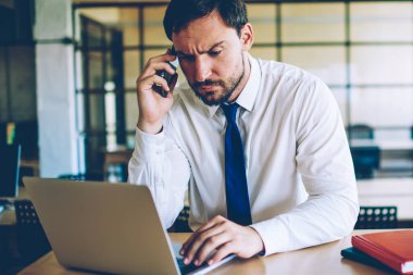Müşteri Hizmetleri için danışmanlık, karışık erkek ofis işçisi cep üzerinden operatör ile konuşurken dizüstü bilgisayar üzerinde dosya indirme sırasında sorun ile şaşkın ciddi işadamı hissi