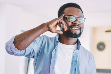 Hafif ferah sınıfta aramak için tablet tutarken parmaklarına dokunan gözlüklü, kendinden emin, Afro-Amerikan bir adam.