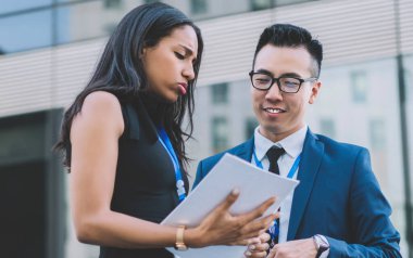 Afrika kökenli Amerikalı bir kadının elinde kağıt yığınıyla konferansta genç bir işadamıyla buluşurken modern binaların karşısında duran