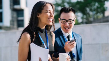 Çeşitli stil sahibi kadın ve erkek kimlikleriyle kahve içip sokakta yürürken akıllı telefonu paylaşıyor ve gün ışığında gülüyorlar.