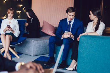 Modern ofis koridorunda bilgisayarlı bulanık siyah bir adam. Çağdaş iş adamlarıyla birlikte cihazlar kullanıyor ve iletişim kuruyor.