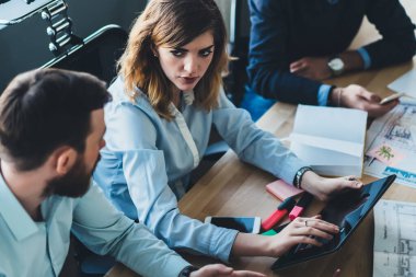 Modern teknoloji, işbirliği ve işbirliği konsepti ile içerik siteleri hakkında yeni fikirler ve bilgiler araştırırken aynı zamanda mimarların çizimleri üzerinde çalışan bir grup zeki tasarımcı.