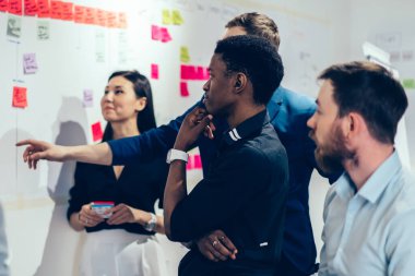 Zeki erkek ve kadın yöneticiler şirket için iş planı üzerinde kafa yoruyor, yaratıcı çeşitlilik grubundan insanlar resmi giyiniyor ve yeni başlayanlar için çubuk üzerine notlar almayı düşünüyorlar.