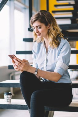 Şirketin internet sitesinde haber okuyan genç zeki bayan yönetici, ofisten ücretsiz kablosuz bağlantı kullanırken, modern cep telefonu uygulaması üzerinden iş arkadaşlarıyla sohbet eden beyaz ekonomist